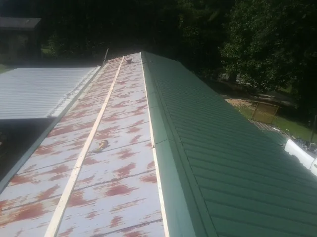 Old rusted panels beside newly installed green metal roofing — Wind Damage Roof Repair by Roofing Brothers in Sheboygan Falls