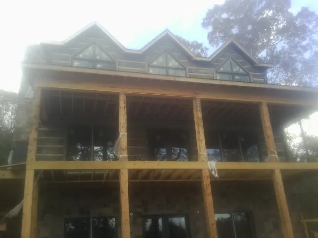 Dormers and porch framing on a large log home under construction — Roof Coating work by our crew in Sheboygan Falls